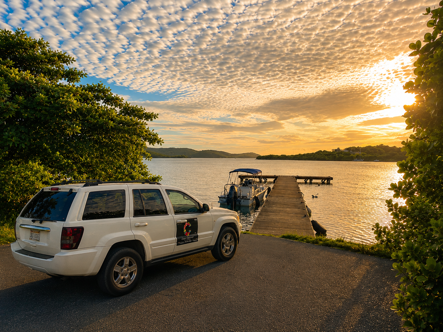 White 2004 Jeep Grand Cherokee with the Casa Carmen logo parked by a wooden dock at sunset in Culebra