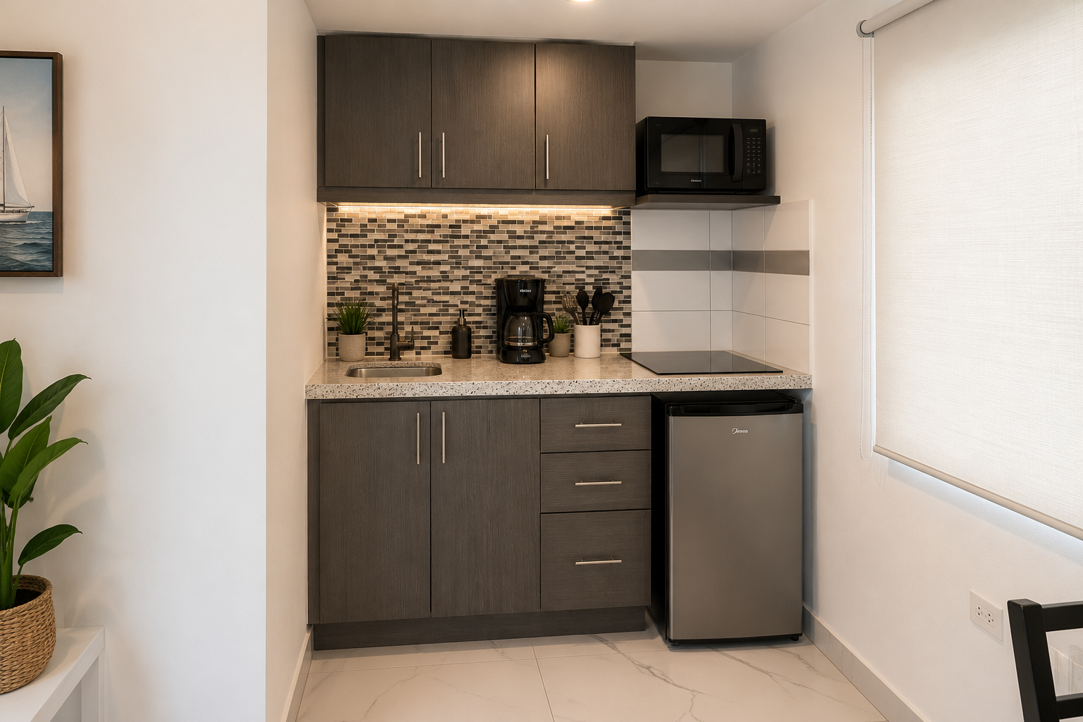 Equipped kitchenette with dark cabinetry, cooktop, microwave, refrigerator and coffee maker