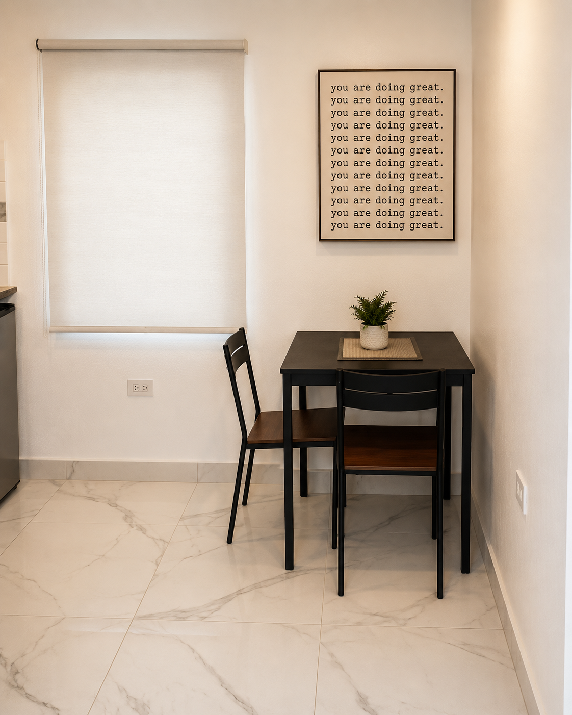 Dining area with a compact table for two and framed art on a bright wall