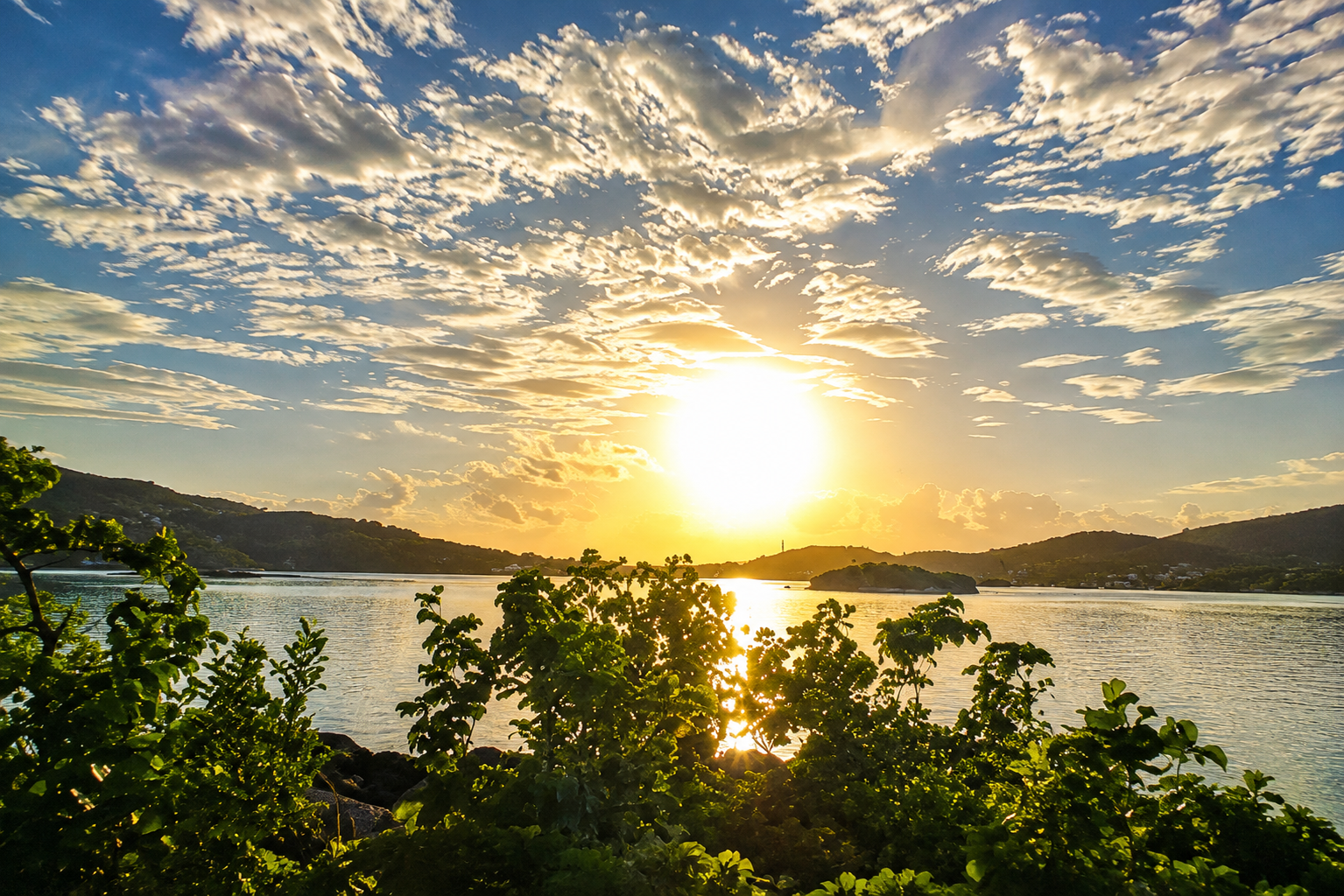 Golden sunset over Ensenada Honda with green hills and calm water in Culebra