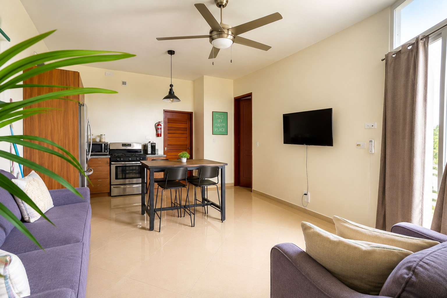 Spacious Suez living area with sofas, dining table, ceiling fan and open kitchen