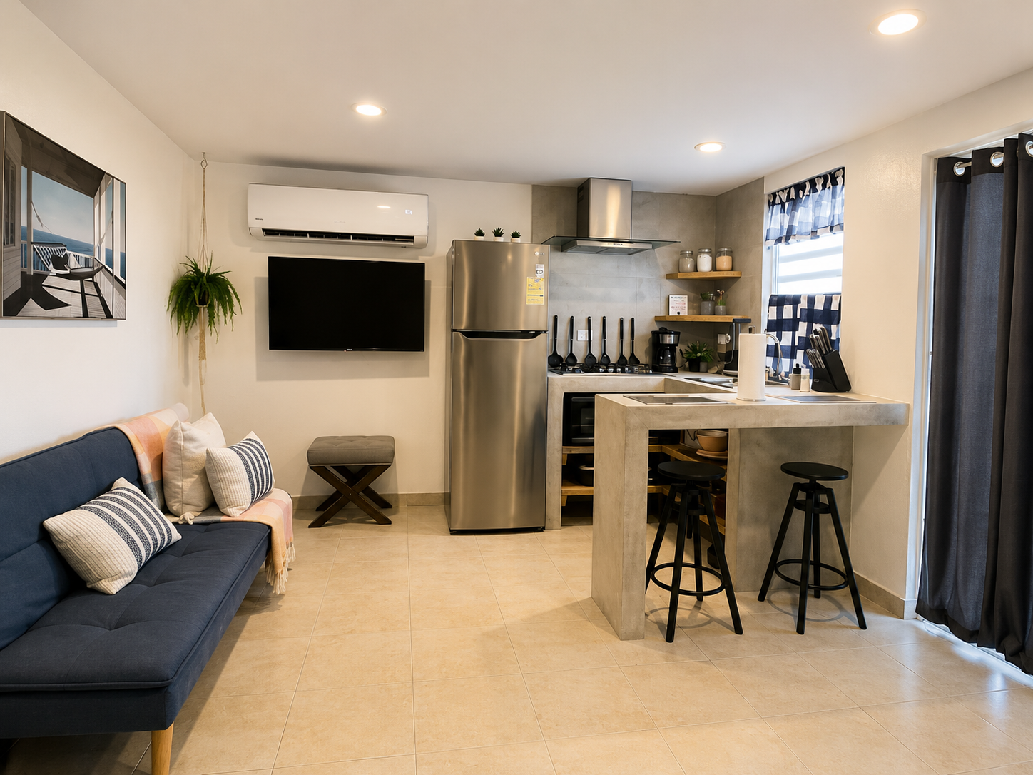 Rota living room with a navy sofa bed, wall-mounted TV and open kitchen with concrete breakfast bar